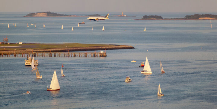 Pleasure boats at Boston Harbor with plane landing at Logan Airport