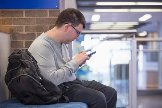 Man with Visual Impairment sitting at school and using his phone