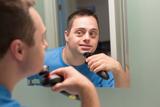 Man with Down Syndrome shaving in bathroom