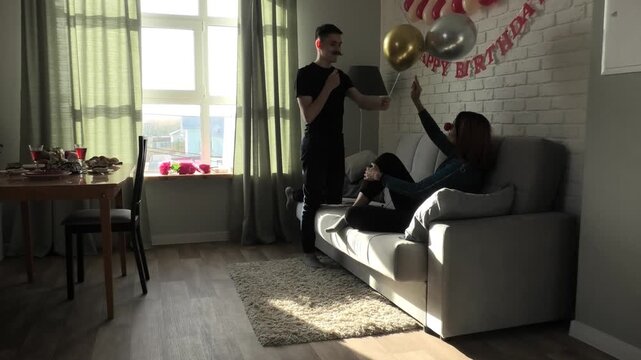 Son tries on moustache and plays with balloons with mom