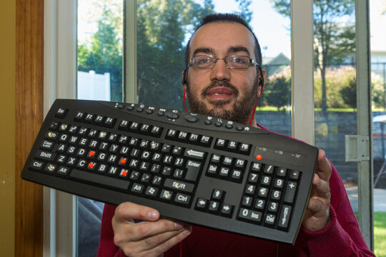 Man with Visual Impairment holding up his keyboard that lets him hear