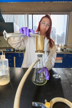 Lab chemist adding sample to filtration strainer