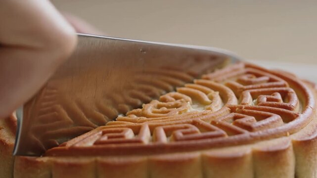 Cutting a decorative pastry with a knife, intricate pattern on golden baked dough