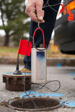 Water department technician lowering leak sensor