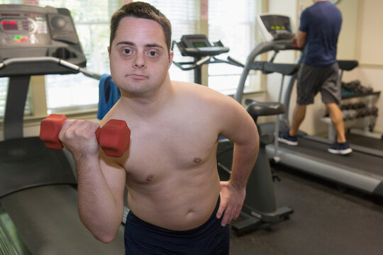 Man with Down Syndrome exercising in a gym with dumbbell