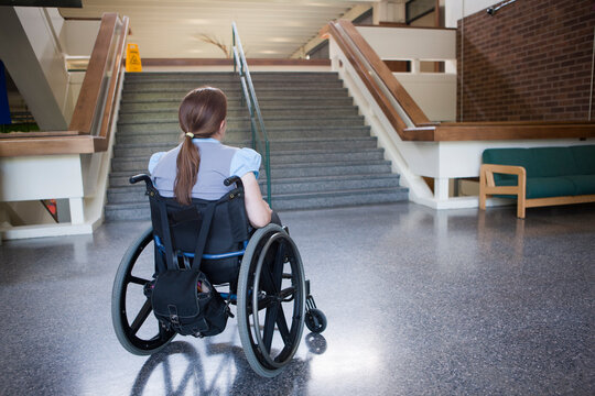 Woman sits in a wheelchair looking at stairs