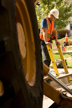 Worker on construction site, industrial truck wheel in foreground