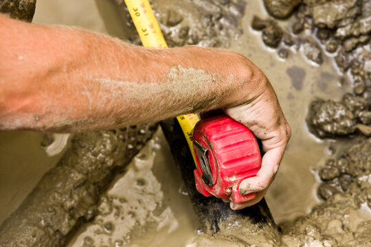 Construction worker using measuring tape in mud
