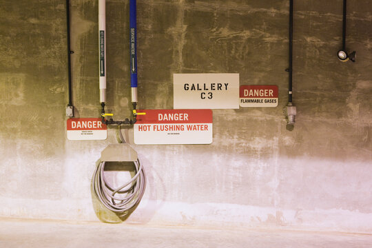 Danger signs with pipe fittings on a wall