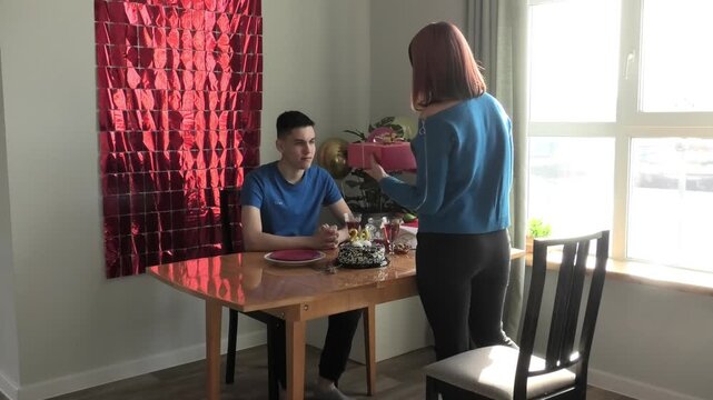 Mother hands her son a box with a gift