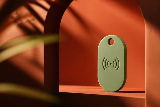 Green NFC tag on orange arch background with soft shadows