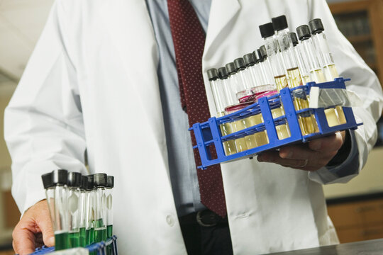 Scientist holding racks of test tubes