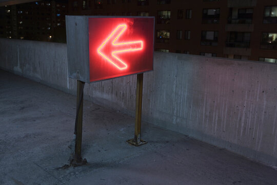 Illuminated arrow sign in a garage, Theater District