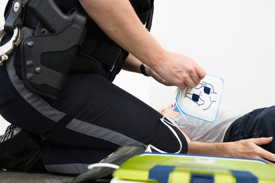 Police woman administering defibrillator to a person
