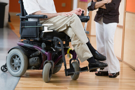 Man in a wheelchair and woman standing with cane