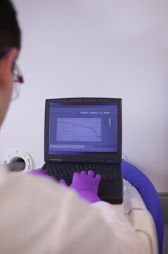 Scientist examining a medical report on a laptop