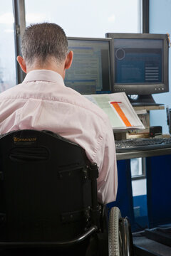Businessman with spinal cord injury in a wheelchair working in an office