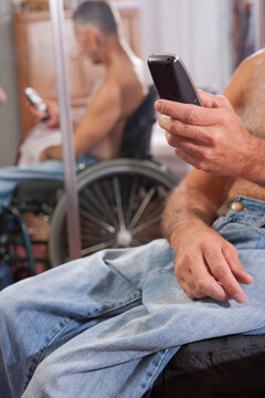 Man with spinal cord injury in a wheelchair using a mobile phone