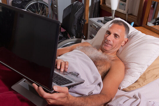 Man with spinal cord injury in the bed using his laptop