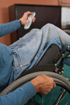 Man with spinal cord injury in a wheelchair using a remote control