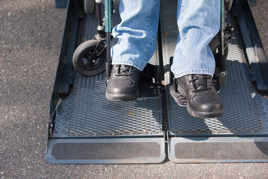 Legs of a man with spinal cord injury in a wheelchair on accessible van ramp