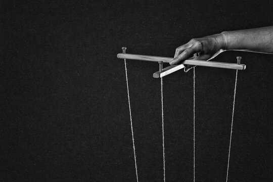 Manipulating Hand with Controlling Strings, Manipulation Concept in Black and White on Textured Paper Background