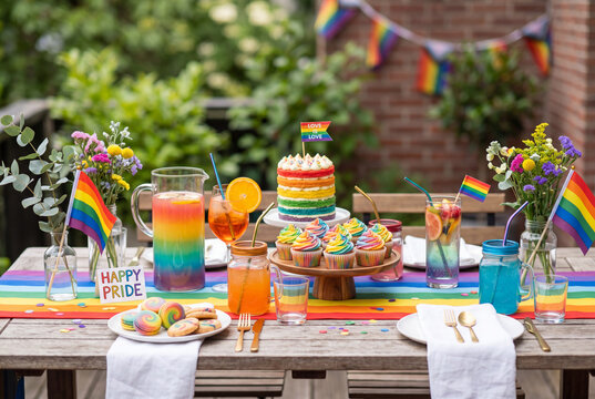 Outdoor table setting for a Pride party with rainbow cake and colorful drinks. LGBTQ celebration with sweet desserts and decorations. Happy Pride concept