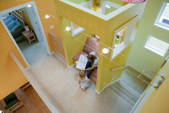 High angle view of a girl reading with her mother in the sitting room of a disability accessible