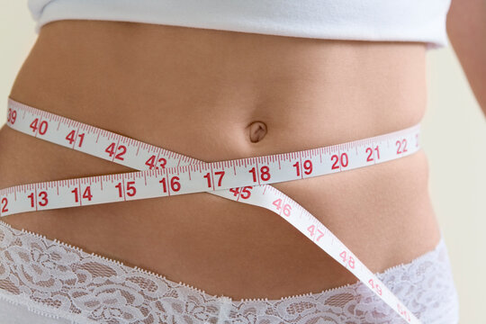 A young woman measuring her waist