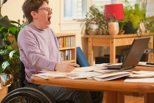 Businesswoman with multiple sclerosis in a wheelchair tired of doing her paperwork