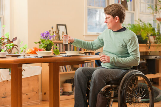 Woman with multiple sclerosis in a wheelchair setting table for dinner