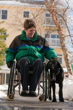 Woman with multiple sclerosis in a wheelchair with a service dog in winter