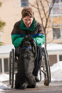Woman with multiple sclerosis playing with a service dog in winter
