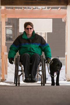 Woman with multiple sclerosis in a wheelchair with a service dog in winter