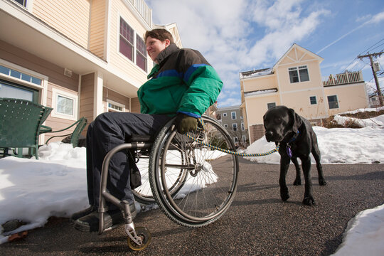 Woman with multiple sclerosis in a wheelchair with a service dog in winter