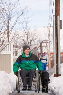 Woman with multiple sclerosis in a wheelchair with a service dog in winter snow