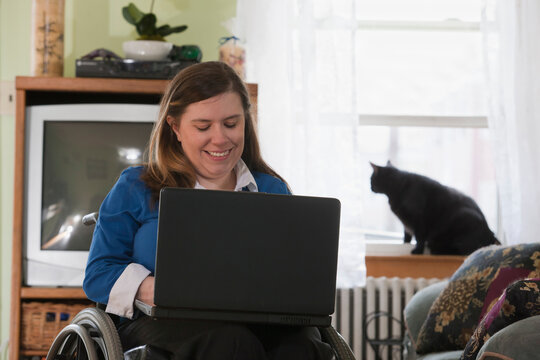 Businesswoman with Spina Bifida in a wheelchair using a laptop at home