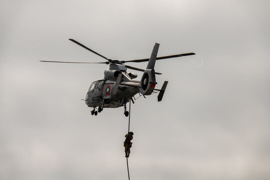 Elite special forces operator fast-roping from a hovering military helicopter during a tactical insertion or rescue mission