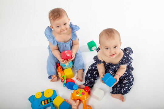 Happy Babies Playing with Colorful Educational Toys on White Background &ndash; Smiling Infants in Stylish Outfits Engaged in Learning and Fun, Perfect for Parenting, Early Childhood, or Toy Ads