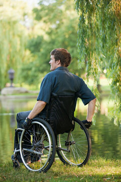 Man with spinal cord injury in a wheelchair enjoying the pond in public park