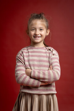 Smiling Little Girl Posing in Studio. Full Length Child Portrait with Playful Expression and Fashionable Clothing