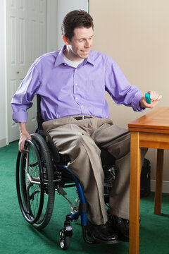 Quadriplegic man in wheelchair with spinal cord injury opening pill case