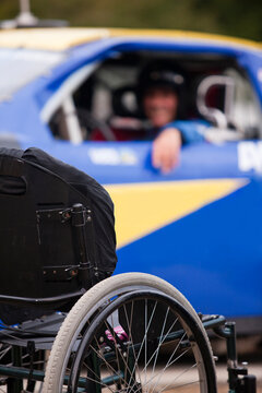 Wheelchair in front of stock car modified for disability racing