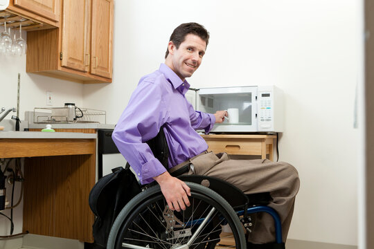 Man in wheelchair with spinal cord injury removing cup from an accessible microwave
