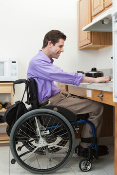 Man in wheelchair with spinal cord injury adjusting heat on an accessible stove