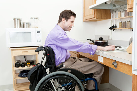 Man in wheelchair with spinal cord injury adjusting heat on an accessible stove