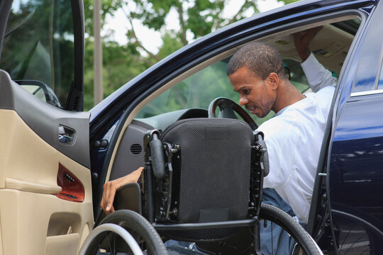 Man who had Spinal Meningitis entering his car with his wheelchair