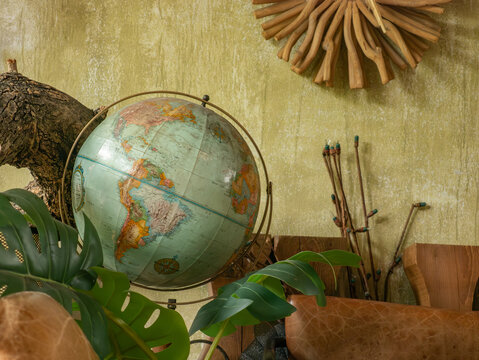 Vintage eclectic cafe interior with distressed leather sofa globe world map monstera plant rustic wood and green wall decor