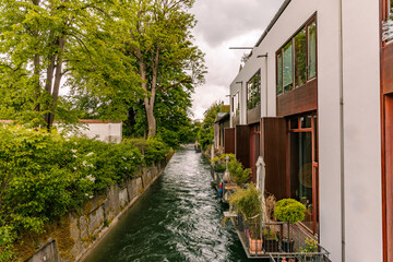 Fototapeta premium Modern residential buildings along the Lech canal in Landsberg am Lech, Bavaria, Germany. Scenic urban waterfront with flowing water, lush greenery and contemporary architecture.
