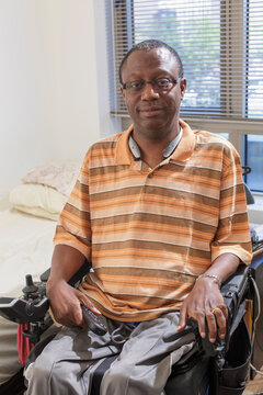 Man with Guillain-Barre Syndrome holding a TV remote in his power chair at home